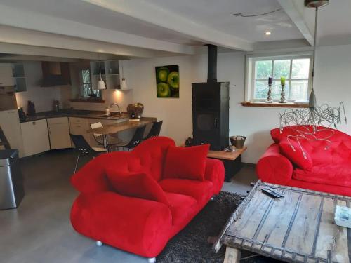 a living room with two red chairs and a kitchen at Country cottage Anna Paulowna, self checkin in Anna Paulowna