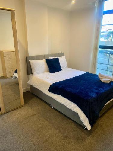 a bedroom with a bed with a blue blanket and a mirror at XL Corner Apartment w Gym & Spa in Manchester
