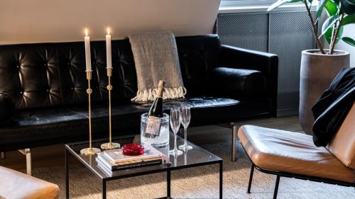 a living room with a black couch with candles on a table at The Duxiana Malmö in Malmö