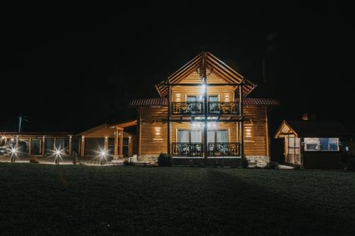 une maison en bois avec des lumières allumées la nuit dans l'établissement Casa Cerbului, à Baia Sprie