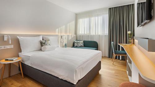 Habitación de hotel con cama grande y escritorio. en Styles Hotel Karlsruhe Messe, en Karlsruhe