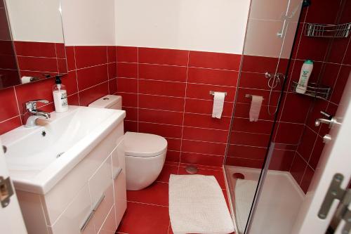 baño de azulejos rojos con aseo y lavamanos en Diseño frente al mar en Portosín, en Portosín