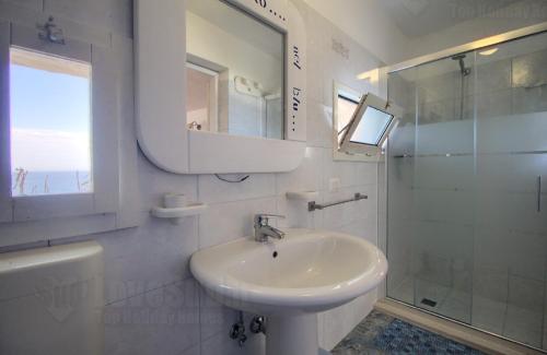 y baño blanco con lavabo y ducha. en Dimora degli Artisti - Ciolo private sea access, en Gagliano del Capo