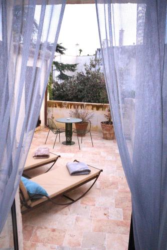 a patio with a table and chairs and curtains at Palazzo Maresgallo Suites & SPA in Lecce