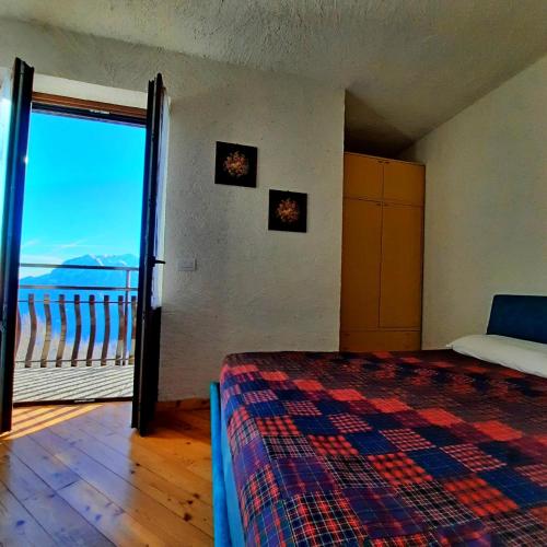 a bedroom with a bed and a view of the ocean at Appartamento Monte Muggio - Your Mountain Holiday in Casargo