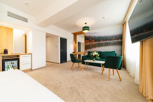 a bedroom with a couch and a table and chairs at Hotel Küküllő - Târnava in Odorheiu Secuiesc