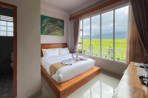 - une chambre avec un lit et une grande fenêtre dans l'établissement RedDoorz Syariah Near Tugu Macan Kayu Aro, à Kayu Aro