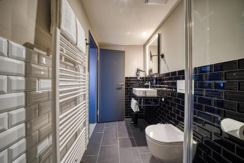 a bathroom with a toilet and a blue door at NYCE Hotel Dortmund Thier Galerie in Dortmund