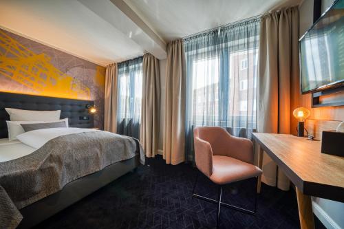 a hotel room with a bed and a desk at NYCE Hotel Dortmund Thier Galerie in Dortmund