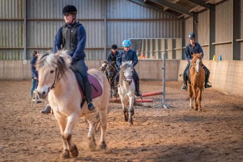 een groep mensen die paardrijden in een gebouw bij The Horse Farm in Garnwerd