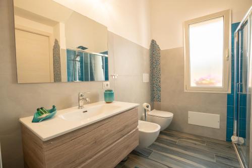 uma casa de banho com um lavatório, um WC e uma janela. em Villa s'ena e su juncu em Loculi