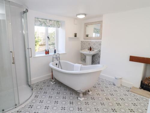 a bathroom with a white tub and a sink at The Old School House in Lower Swell