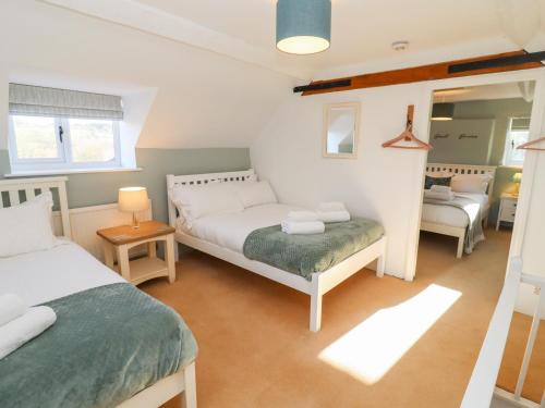 a bedroom with two beds and a mirror at The Old School House in Lower Swell