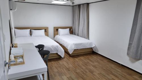 Habitación con 2 camas, mesa y escritorio. en The Oakra Hotel, en Jeju