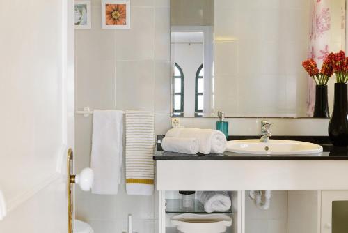 ein weißes Badezimmer mit einem Waschbecken und einem Spiegel in der Unterkunft Luzias Apartment in Funchal