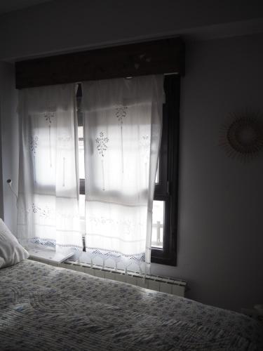 a bedroom with a window with white curtains at Las Calendas de Atapuerca CB in Castrillo del Val