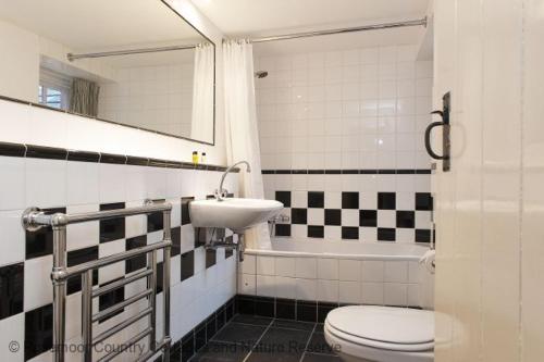 Un baño con lavabo, inodoro y espejo. en Holly Tree, en Haverfordwest