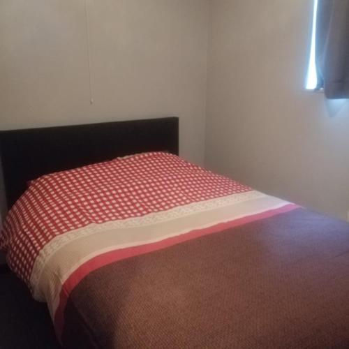 a bedroom with a bed with a red and white comforter at Maison Bonne Humeur Achouffe in Houffalize