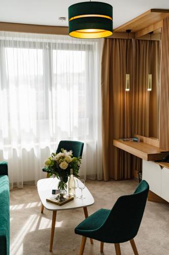 a living room with two chairs and a table with flowers on it at Hotel Küküllő - Târnava in Odorheiu Secuiesc