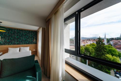 a hotel room with a bed and a large window at Hotel Küküllő - Târnava in Odorheiu Secuiesc