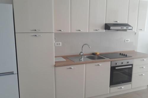 eine weiße Küche mit weißen Schränken und einem Waschbecken in der Unterkunft Apartman Ivan in Kaštela