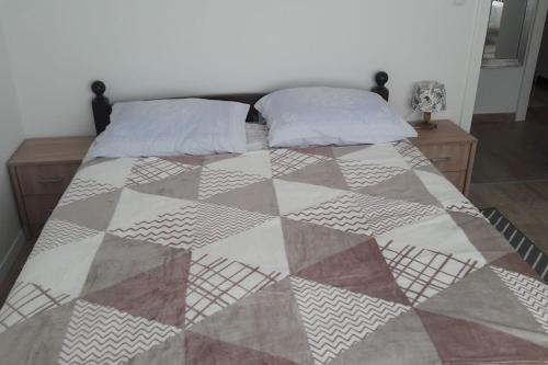 ein Bett mit einer Decke und zwei Kissen darauf in der Unterkunft Apartman Ivan in Kaštela