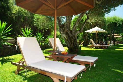 two lounge chairs and a table with an umbrella at Fiori Hotel in Gouvia