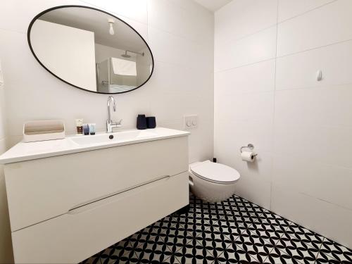 Baño blanco con lavabo y espejo en 8 Hulda - By Beach Apartments TLV, en Tel Aviv