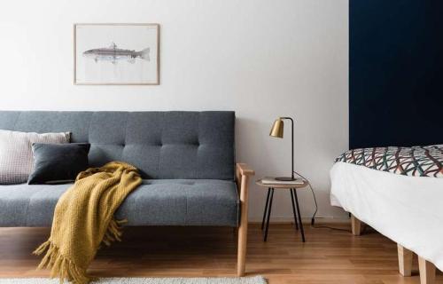 a bedroom with a blue couch and a bed at PunavuoriPad - Modern Apt. with Park Views in Design District in Helsinki