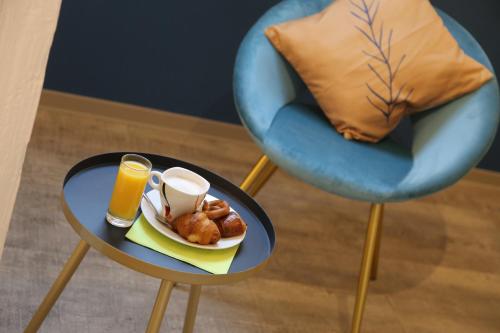a table with a plate of food and a glass of orange juice at Hotel Victoria in Strasbourg