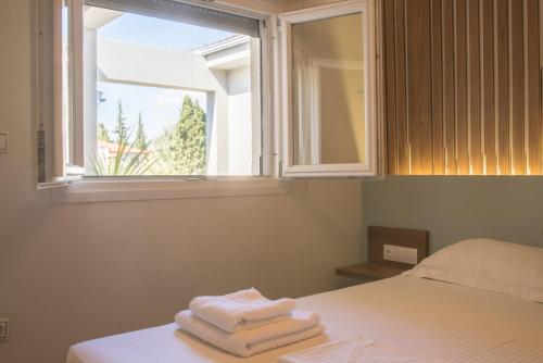 una pila de toallas sentadas en una cama con ventana en Vertigo Seaside Apartments, en Nikiti