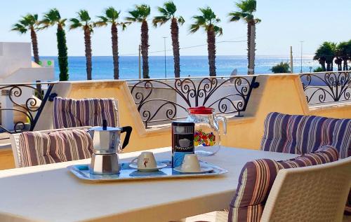 a table with two coffee makers on a balcony with palm trees at Torre Vado Appartamento Vista Mare in Torre Vado
