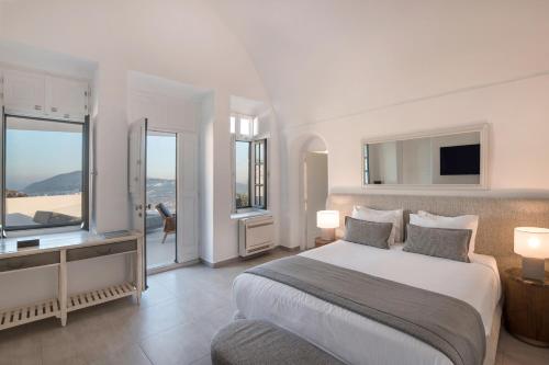 a bedroom with a large bed and a large window at Aqua Luxury Suites by NOMÉE Hospitality Group in Imerovigli