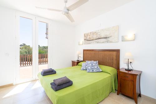 a bedroom with a green bed and a balcony at Apartament Cala Anguila in Manacor