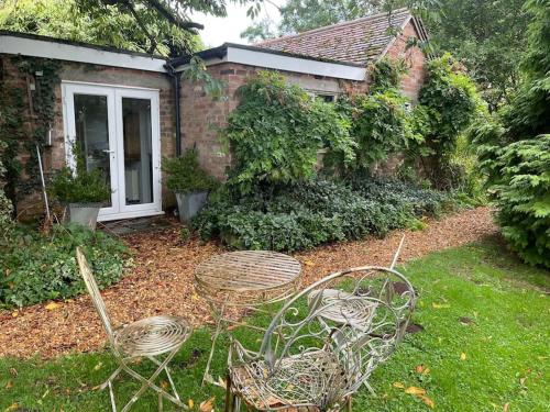 a yard with two chairs and a house at The Big Cosy Boudoir Bed + Hot tub in Harvington