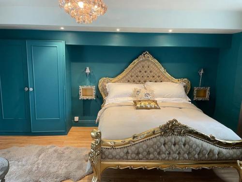 The Big Cosy Boudoir Bed + Hot tub في Harvington: غرفة نوم بسرير كبير بجدار ازرق