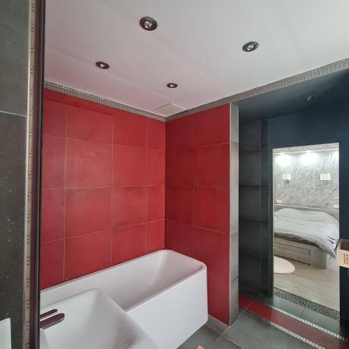 - une salle de bains rouge avec baignoire et une chambre dans l'établissement Appartement très lumineux porte de Saint-Cloud - F3 avec suite parentale, à Paris