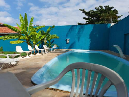 una piscina con una silla junto a una pared azul en Pousada Hotel Canto dos Mares, en Guarujá