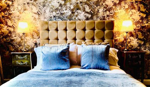 una camera da letto con un grande letto con cuscini blu di The Capon Tree Town House a Jedburgh