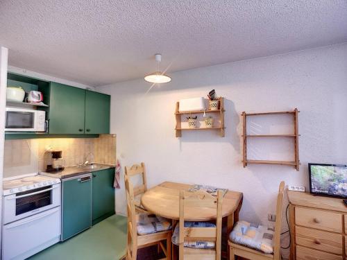 une cuisine avec des placards verts et une table en bois dans l'établissement Studio 4 pers, skis aux pieds, cuisine équipée - FR-1-178-321, aux Menuires