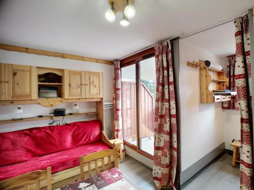 - un canapé rouge dans une chambre avec fenêtre dans l'établissement Beau 2 pièces 4 pers 24m² ski aux pieds, commerces à proximité, parking gratuit - FR-1-178-340, aux Menuires