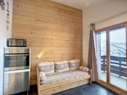 Cette chambre est dotée d'un mur en bois avec un banc et une fenêtre. dans l'établissement Beau 2P rénové 24m², ski aux pieds, balcon, parking, animaux admis - FR-1-178-357, aux Menuires