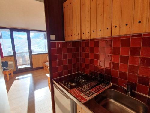 - une cuisine avec un évier et du carrelage rouge sur le mur dans l'établissement Studio idéalement situé, 2 pers, pied des pistes - FR-1-178-355, aux Menuires