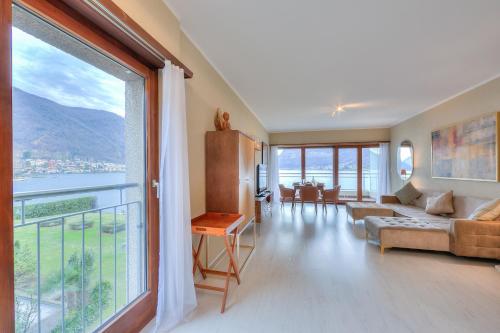 een woonkamer met een bank en een groot raam bij Emotion Lake View - Happy Rentals in Capolago