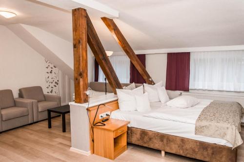 ein Schlafzimmer mit einem großen Bett und einem Stuhl in der Unterkunft Wellness- & Sporthotel Haus am See in Arendsee