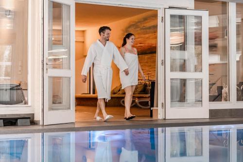 a man and a woman walking through a doorway at Wellness- & Sporthotel Haus am See in Arendsee