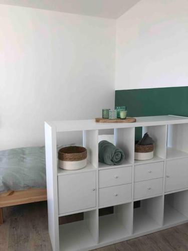 une étagère blanche avec des paniers dans une pièce dans l'établissement Maison sur la place du village d’Ourville en Caux, à Ourville-en-Caux