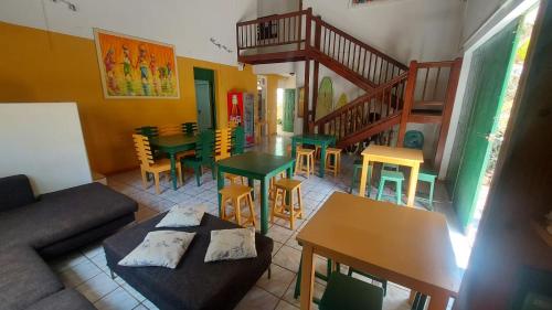 a living room with a couch and tables and chairs at Surf House Hostel in Santa Maria