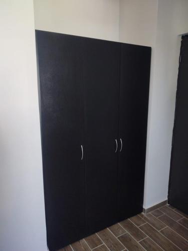 un armario negro en la esquina de una habitación en recamara en Departamento amueblado en Monterrey