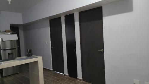 un pasillo con puertas negras en una habitación en recamara en Departamento amueblado en Monterrey